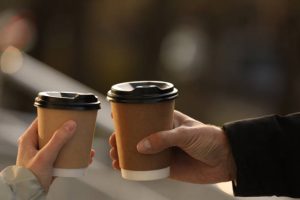 couple with takeaway coffee cups outdoors, closeup